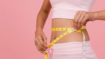 woman measuring herself after achieving a healthy weight thanks to her nutritionst